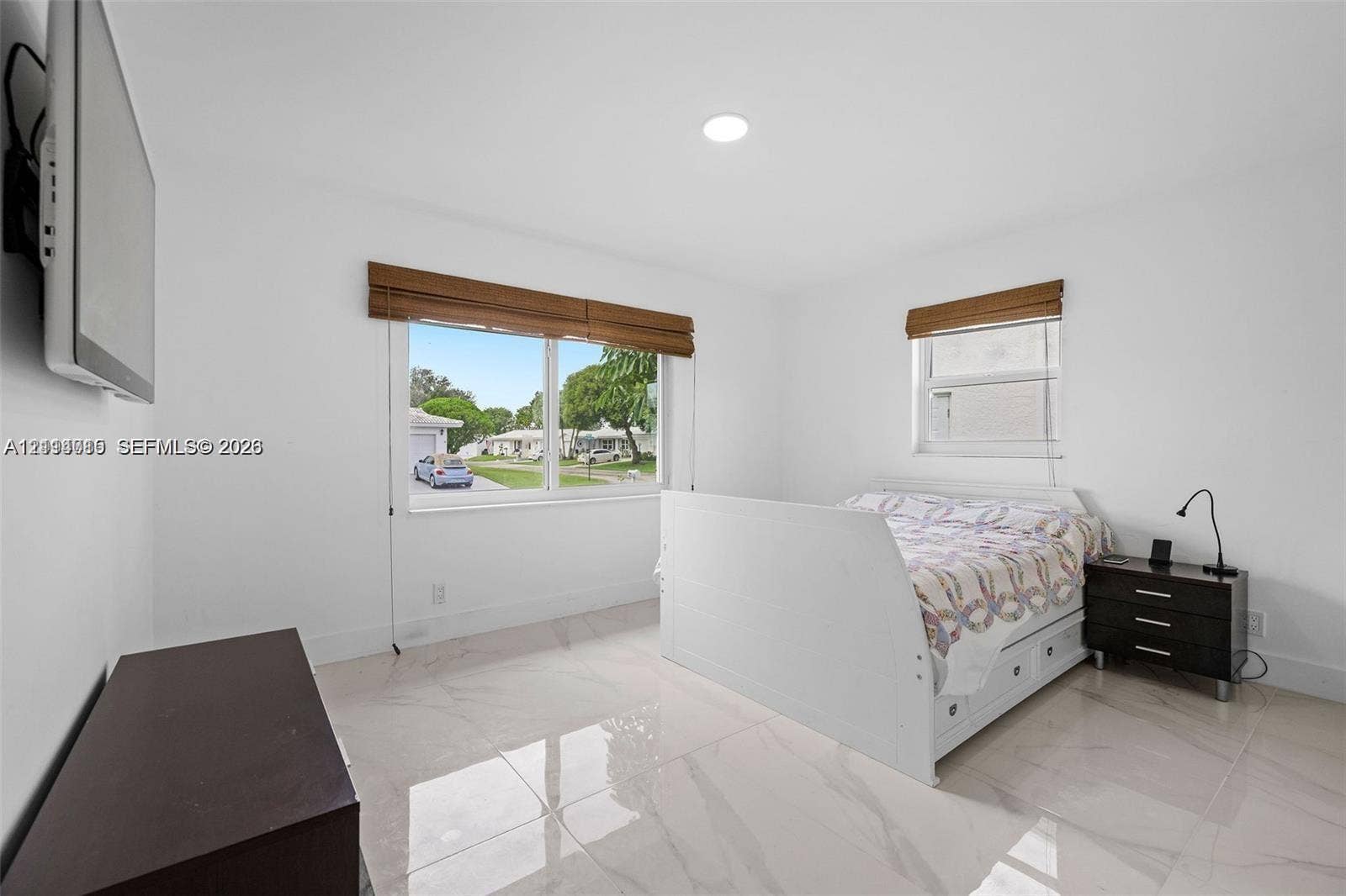 Large-format polished tile flooring, recessed ceiling lighting, and windows finished with woven wood shades