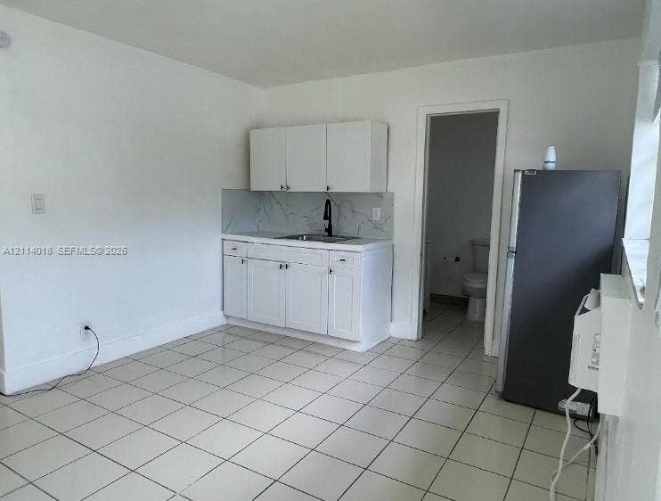 6029 Polk Street, #1B, Hollywood, Hollywood, FL 33024 Kitchenette featuring white cabinetry, stone-patterned backsplash, stainless steel sink, matte black gooseneck faucet, and tile flooring