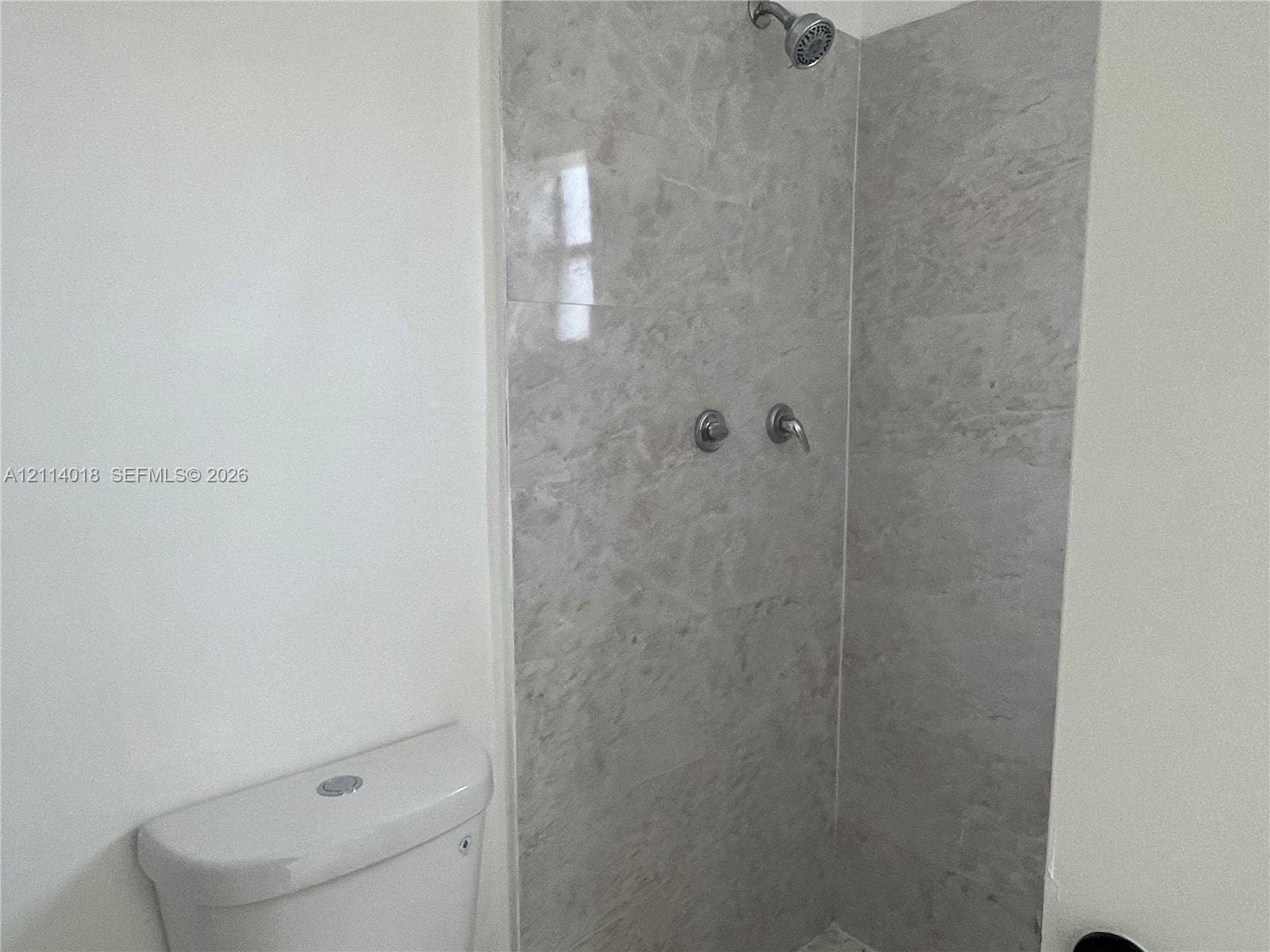6029 Polk Street, #1B, Hollywood, Hollywood, FL 33024 Walk-in shower enclosure featuring large-format grey stone-finish tile surround, wall-mounted shower head, and chrome-finish plumbing fixtures