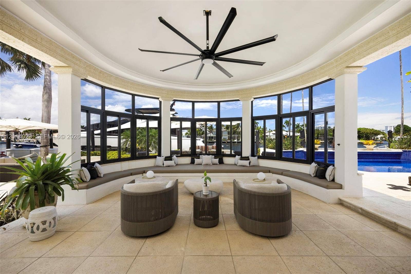 Covered semi-circular patio featuring stone-tile flooring, a large overhead ceiling fan, and built-in masonry bench seating