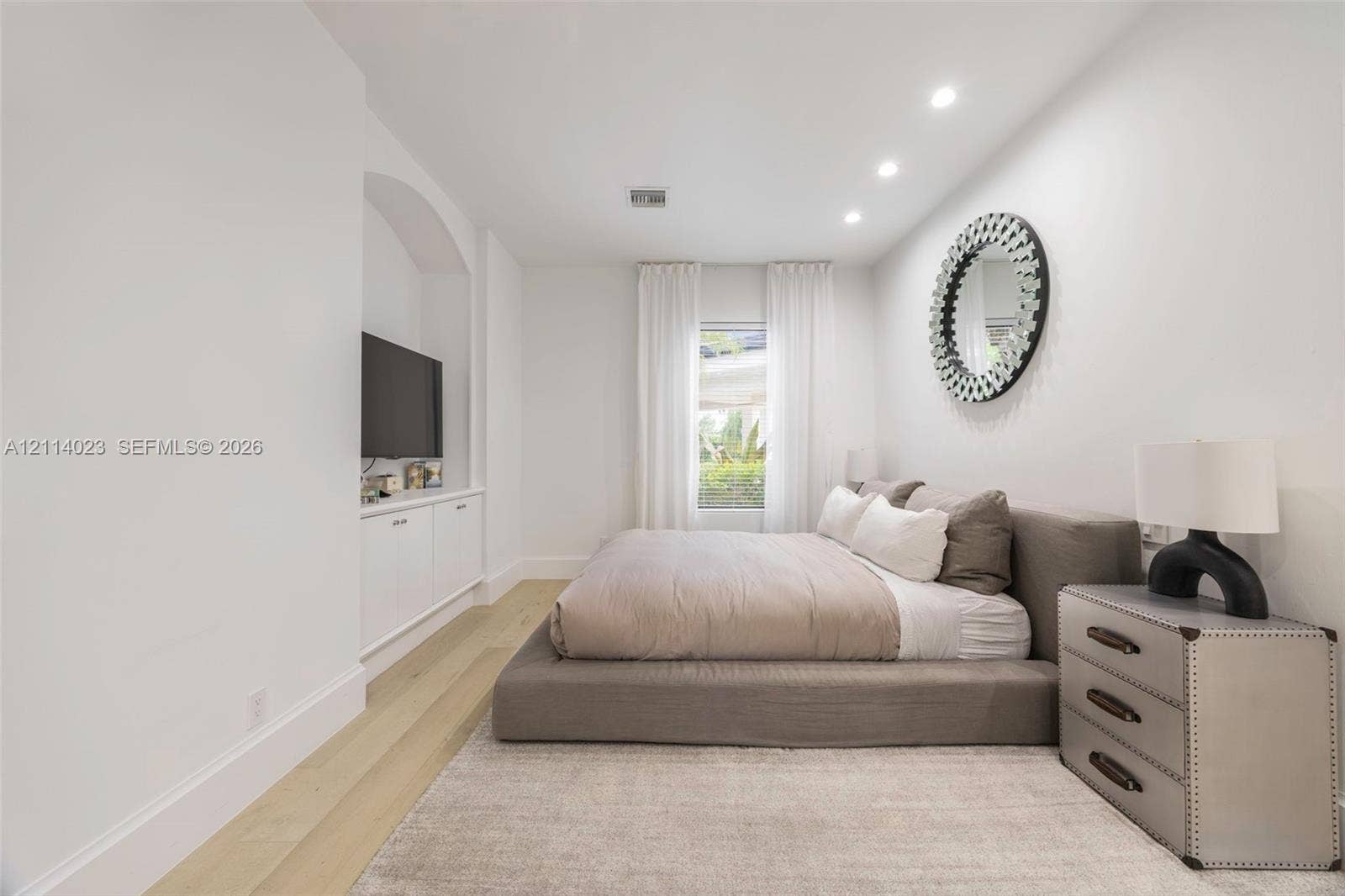 Bedroom featuring wood-finish flooring, recessed lighting, and a built-in arched media niche with cabinetry