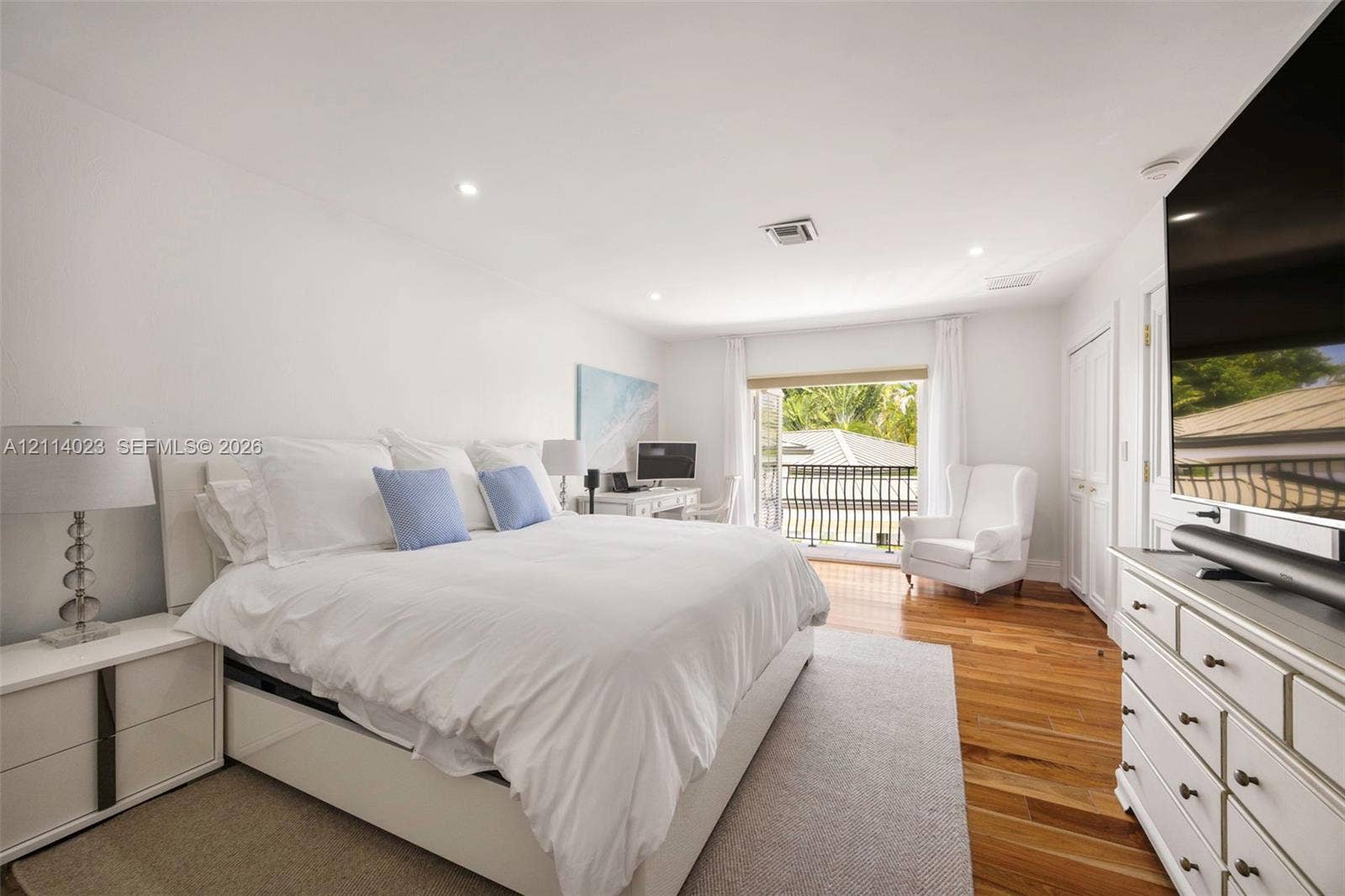 Wood-finish flooring, recessed lighting, and a balcony with decorative metal railing