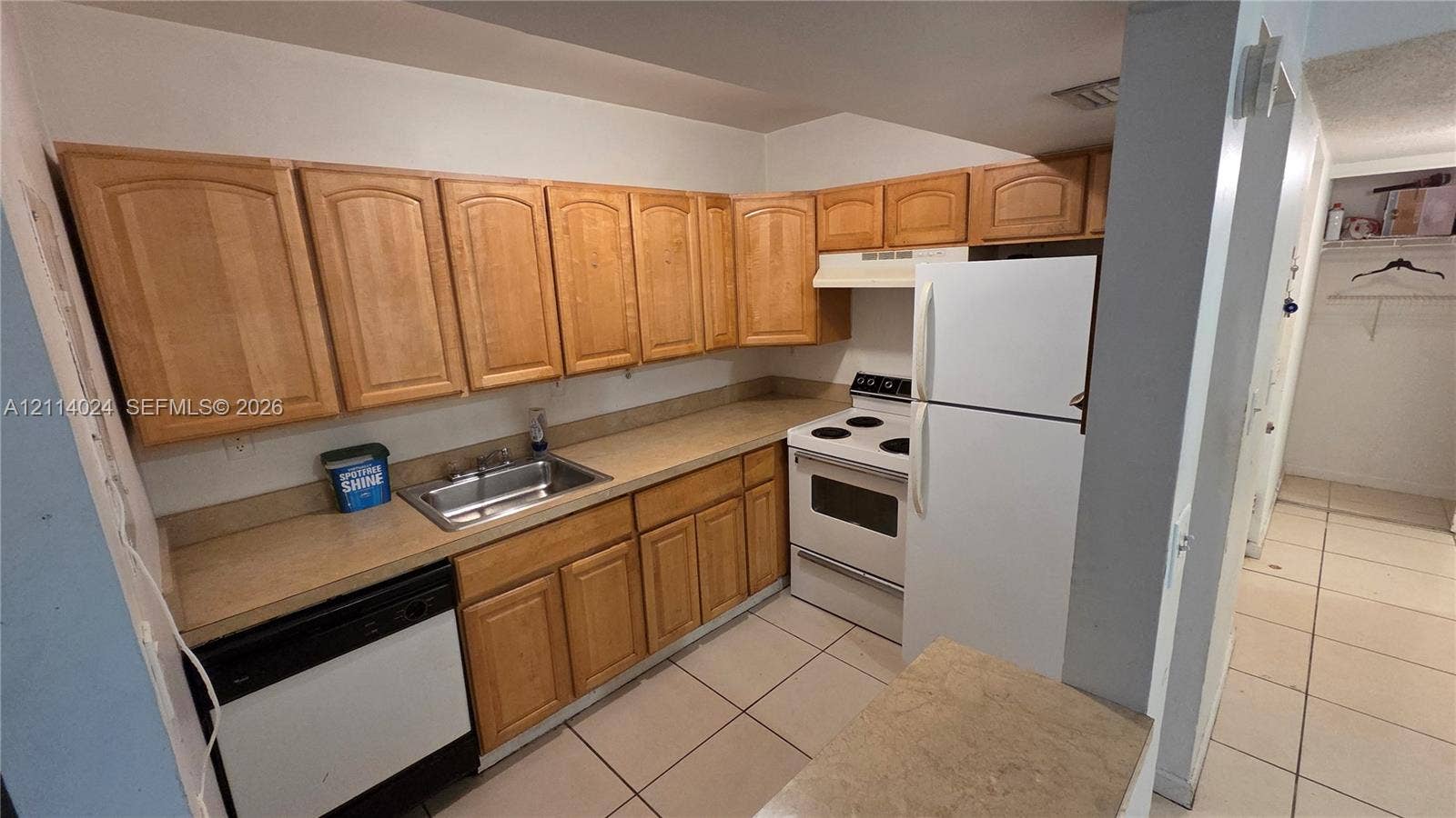 505 S Pine Island Road, #B205, Plantation, FL 33324 Kitchen featuring wood cabinetry, integrated stainless steel sink, solid-surface countertops, and tile flooring