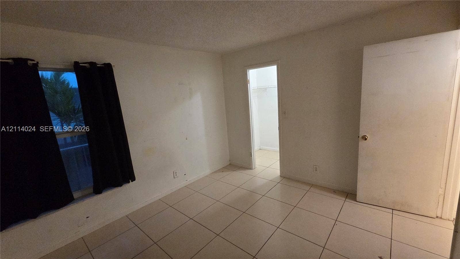 505 S Pine Island Road, #B205, Plantation, FL 33324 Neutral-toned interior space featuring light-colored tile flooring, a window, and a door providing entry to a storage closet
