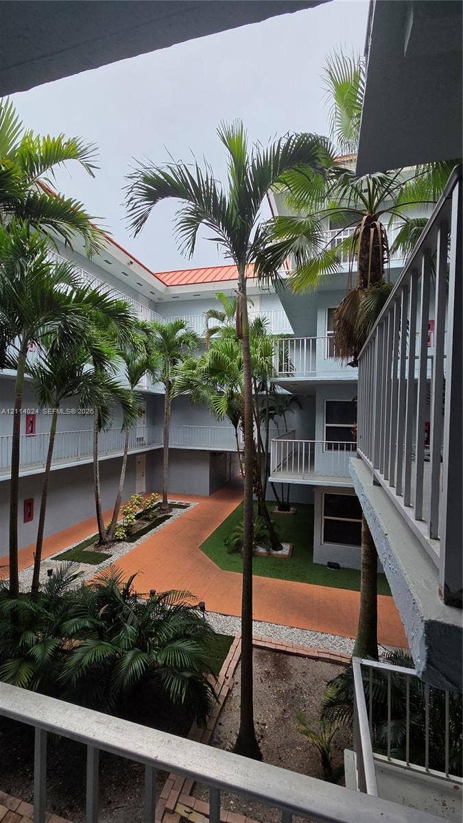 505 S Pine Island Road, #B205, Plantation, FL 33324 Central courtyard featuring palm trees, tiered balconies with metal railings, a paved walkway, and maintained greenery
