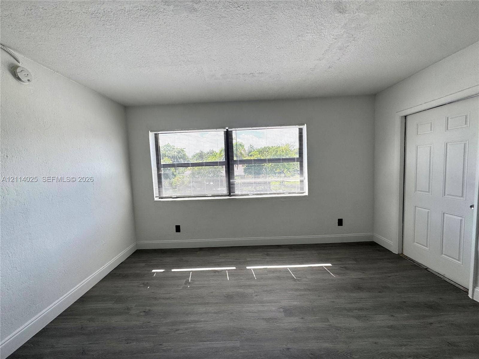 1505 NE 135th Street, #10, North Miami, North Miami, FL 33161 Interior room featuring neutral wall finishes, wood-finish flooring, a multi-pane window, and a six-panel door