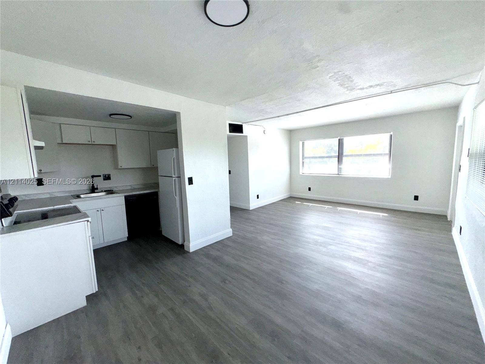 1505 NE 135th Street, #10, North Miami, North Miami, FL 33161 Kitchen featuring white cabinetry, wood-finish flooring, and a large window