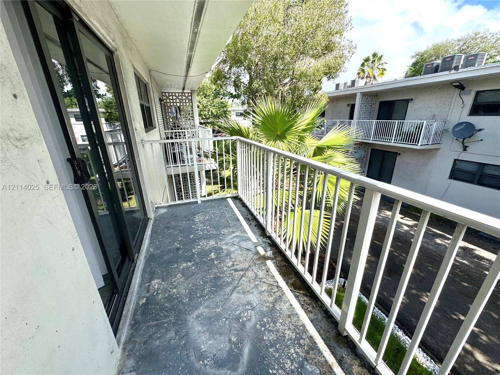 1505 NE 135th Street, #10, North Miami, North Miami, FL 33161 Covered balcony featuring white metal railings, sliding glass door, and solid surface flooring