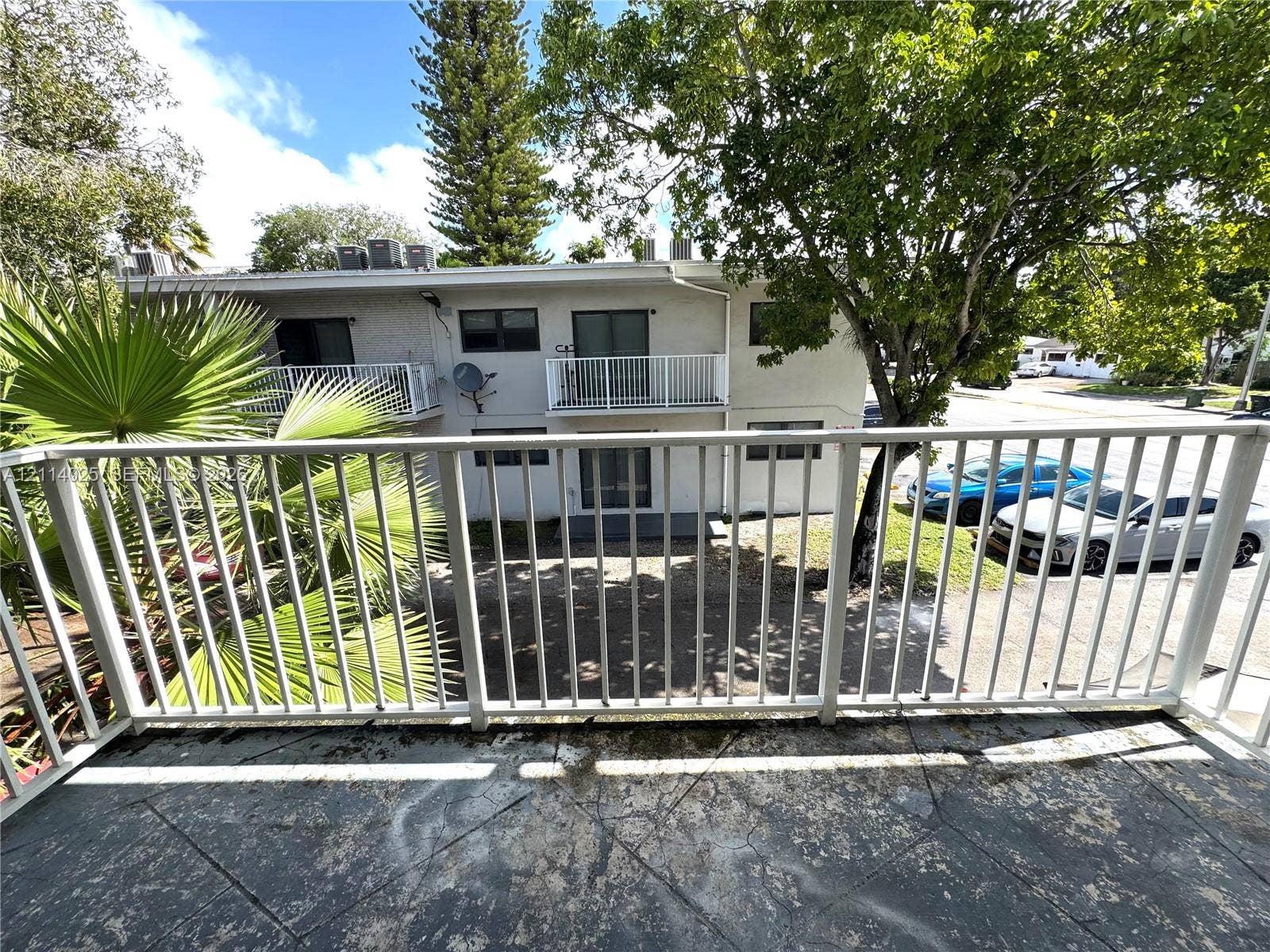 1505 NE 135th Street, #10, North Miami, North Miami, FL 33161 Private balcony featuring white metal railings and concrete flooring with mature palm and broadleaf trees