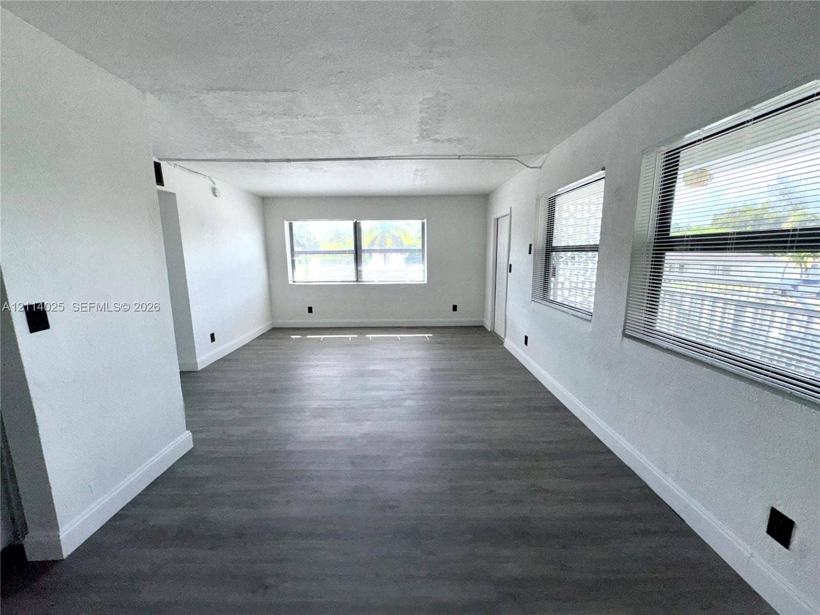 1505 NE 135th Street, #10, North Miami, North Miami, FL 33161 Neutral interior space featuring wood-finish flooring, multi-pane windows, and minimalist wall finishes