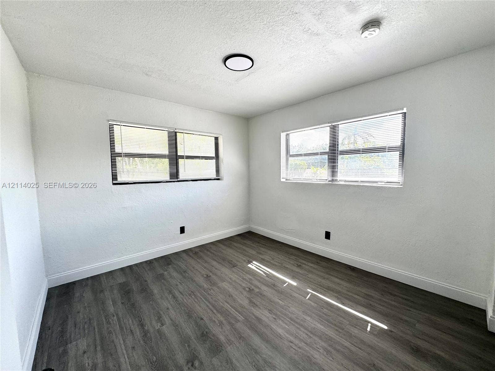 1505 NE 135th Street, #10, North Miami, North Miami, FL 33161 Room featuring wood-finish flooring, white walls, dual windows with integrated blinds, and flush-mount ceiling lighting