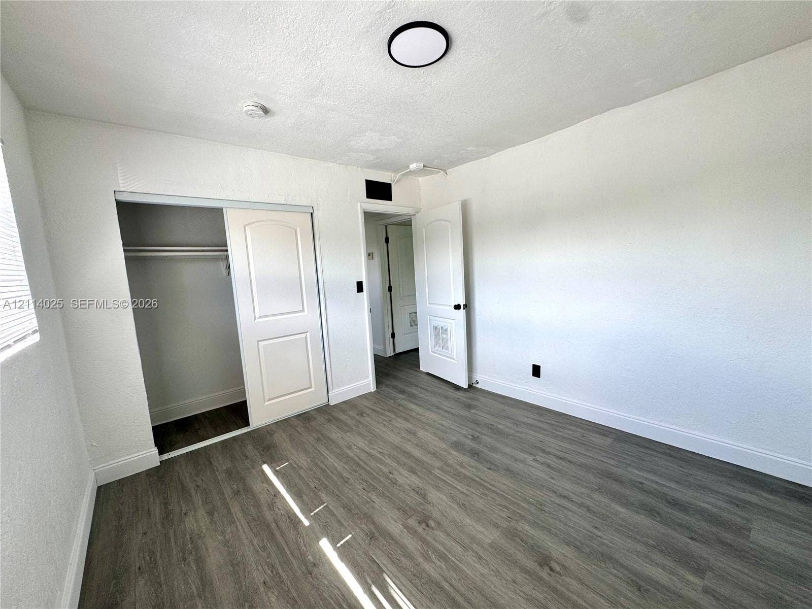1505 NE 135th Street, #10, North Miami, North Miami, FL 33161 Room featuring wood-finish flooring, two-panel interior doors, a sliding closet door, and a flush-mount circular ceiling light