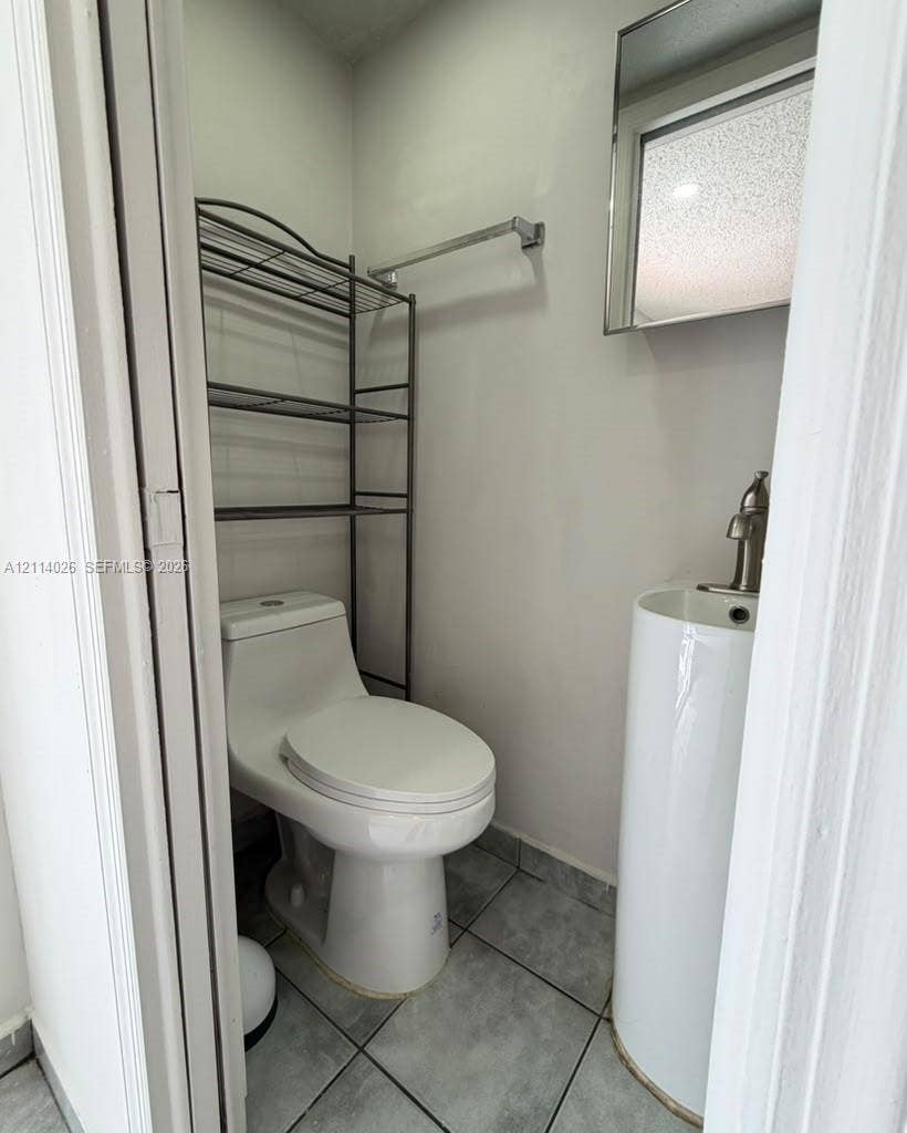 11511 SW 180th Street, #Studio, Miami, Miami, FL 33157 Compact restroom featuring a white pedestal sink with a single-handle faucet, a one-piece elongated toilet, and grey tile flooring