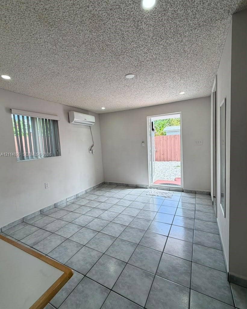 11511 SW 180th Street, #Studio, Miami, Miami, FL 33157 Interior space featuring ceramic tile flooring, recessed lighting, wall-mounted air conditioning unit, and a glass-paneled exterior door
