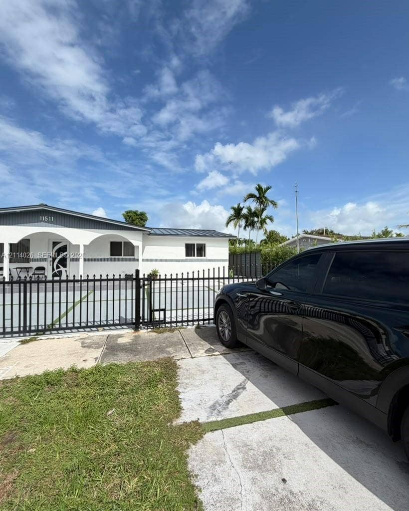 11511 SW 180th Street, #Studio, Miami, Miami, FL 33157 Single-story exterior featuring a metal roof, arched covered entryway, and a secured perimeter with a decorative metal fence
