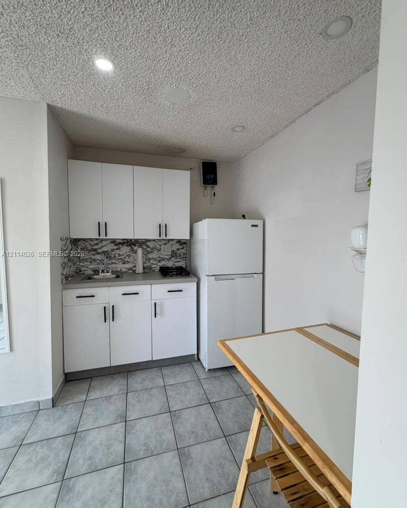 11511 SW 180th Street, #Studio, Miami, Miami, FL 33157 Kitchenette featuring white cabinetry, a stone-patterned backsplash, neutral countertops, recessed lighting, and ceramic tile flooring