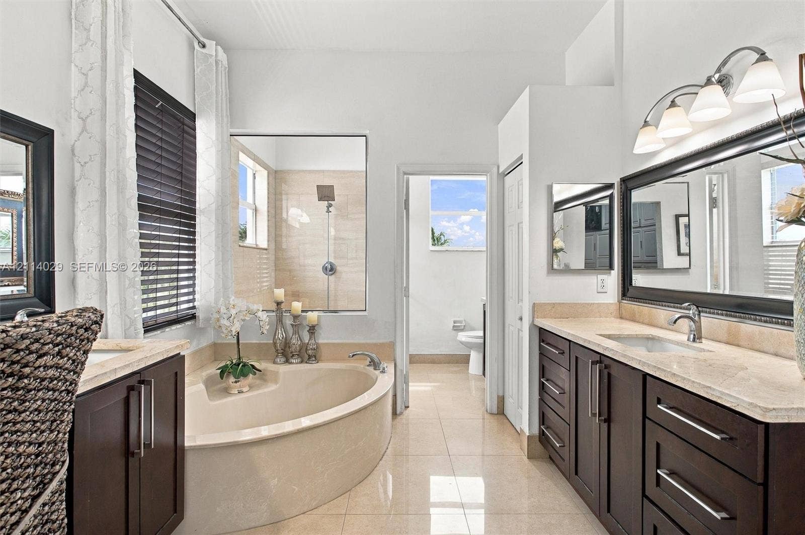 5257 SW 158th Avenue, Miramar, FL 33027 Dual-vanity cabinetry with stone-finish countertops, corner soaking tub, large-format tile flooring, walk-in shower with tiled surround, and multi-light vanity fixtures