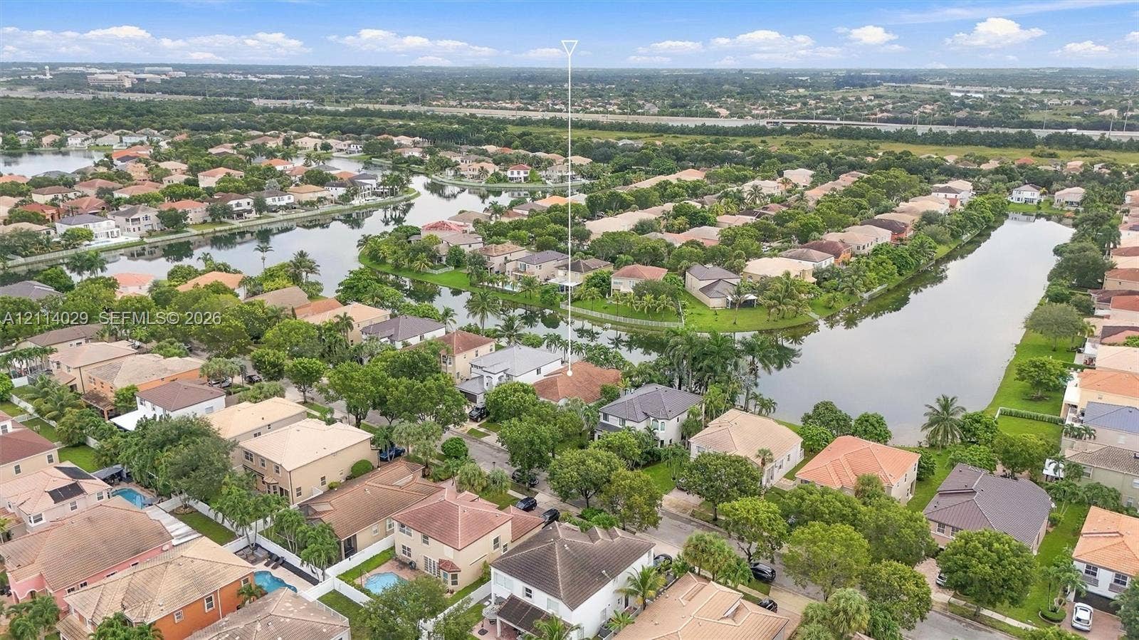 5257 SW 158th Avenue, Miramar, FL 33027 Aerial perspective featuring a residential property situated on a waterway with mature trees and a tile roof