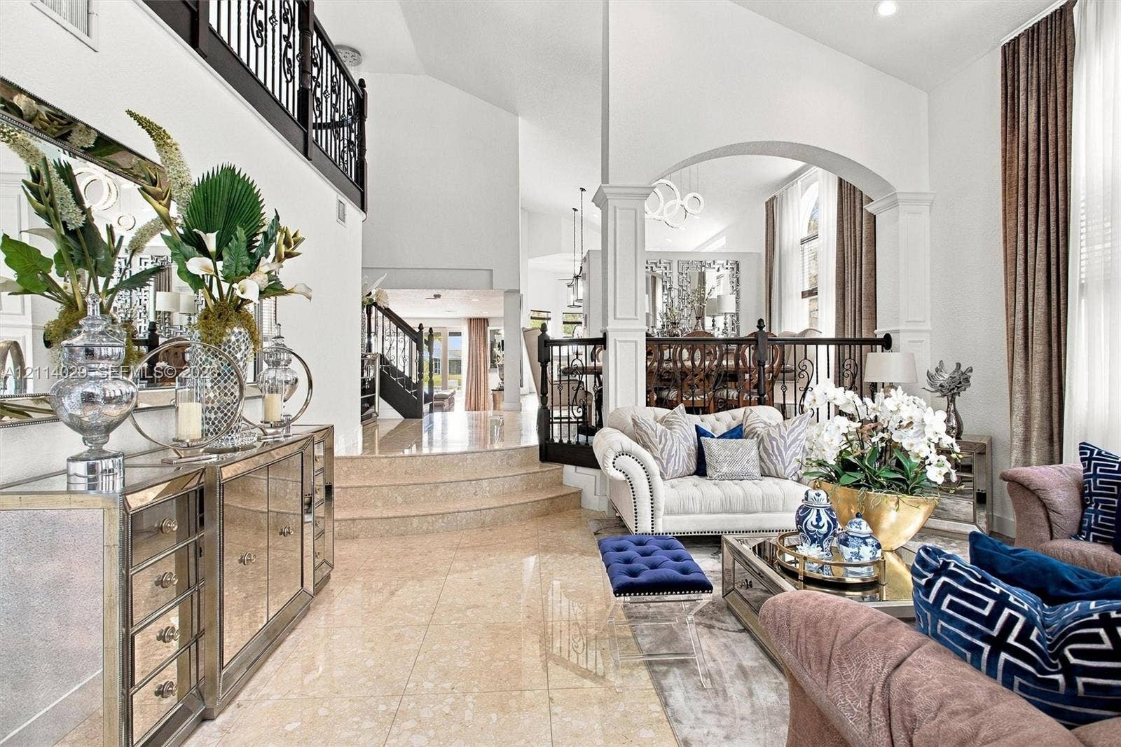 5257 SW 158th Avenue, Miramar, FL 33027 High-ceiling living area featuring stone tile flooring, an elevated platform, arched architectural detailing, and ornamental metal railings