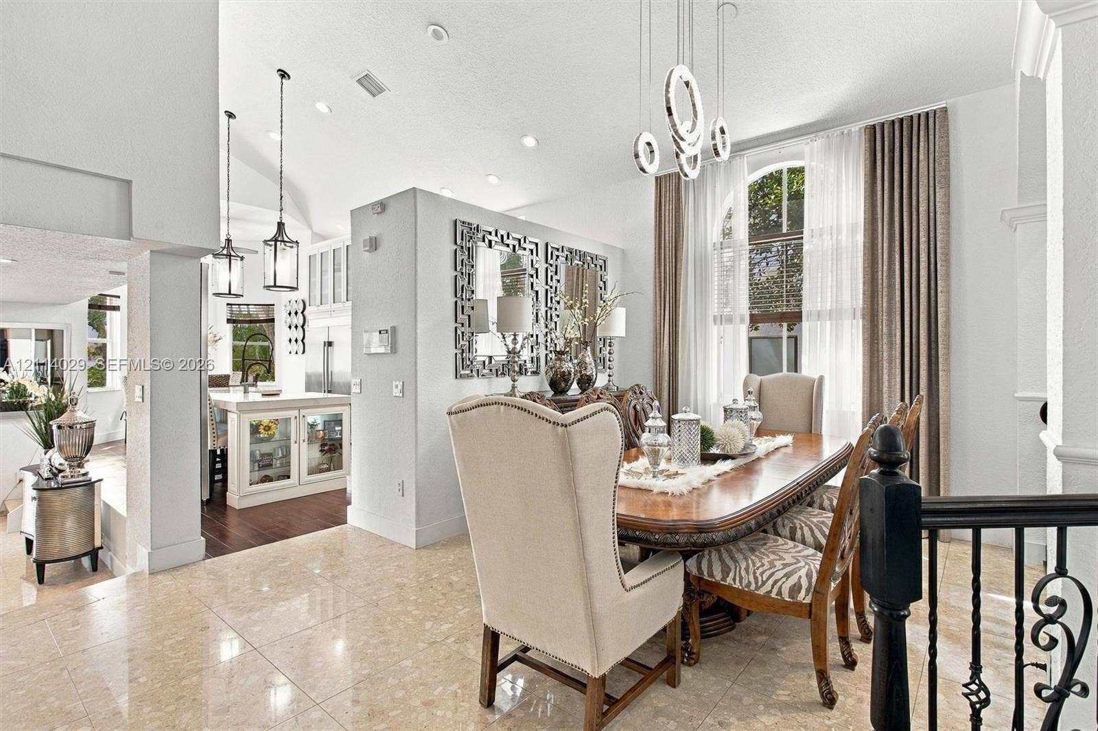 5257 SW 158th Avenue, Miramar, FL 33027 Open-concept dining area featuring vaulted ceilings, polished stone flooring, custom architectural recessed lighting, modern geometric pendant chandeliers, and an arched window