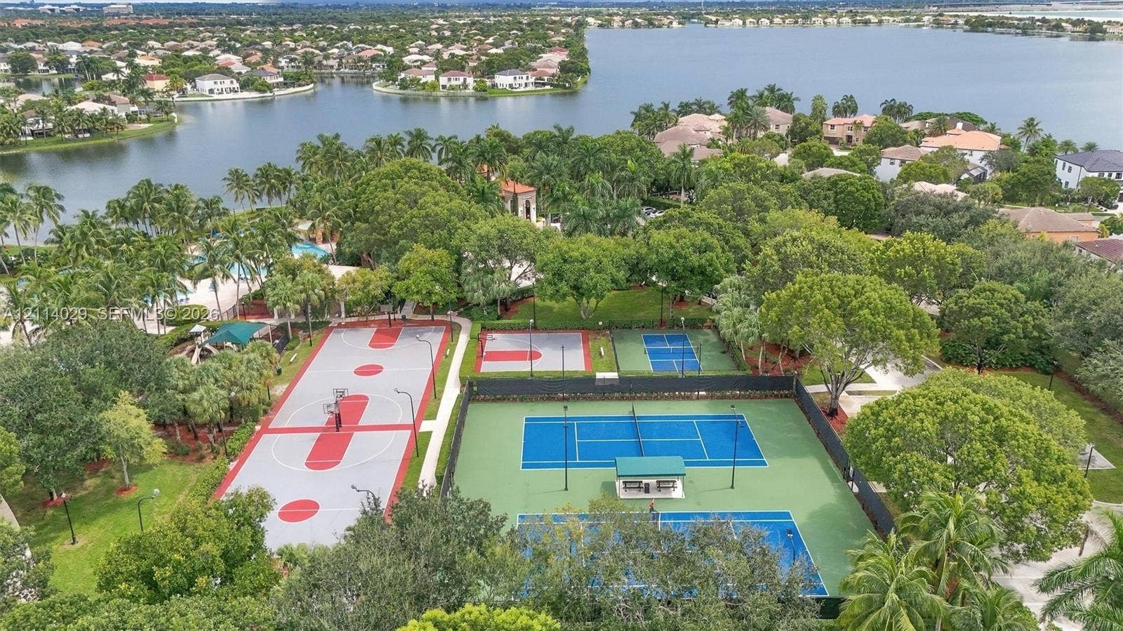 5257 SW 158th Avenue, Miramar, FL 33027 Recreational area featuring fenced tennis courts, a multi-sport court, and mature landscaping