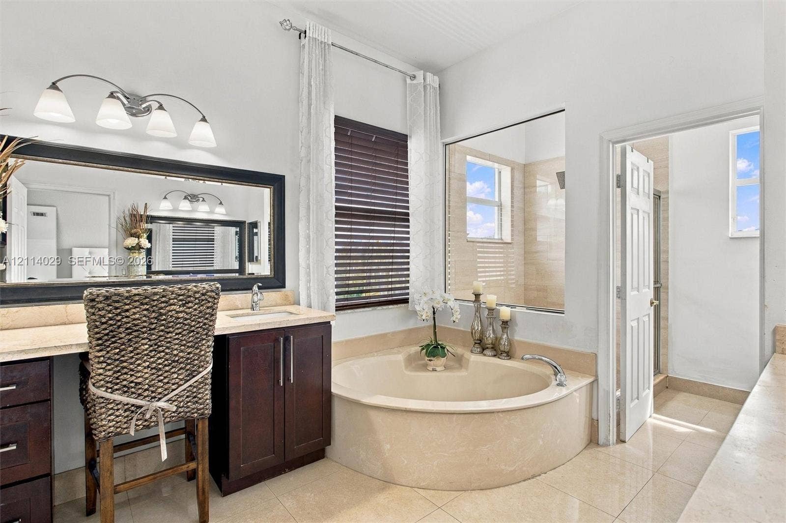 5257 SW 158th Avenue, Miramar, FL 33027 Built-in dark wood vanity with a stone countertop, oversized rectangular mirror, built-in soaking tub with stone surround, tile flooring, and integrated wall-to-wall mirror partitioning