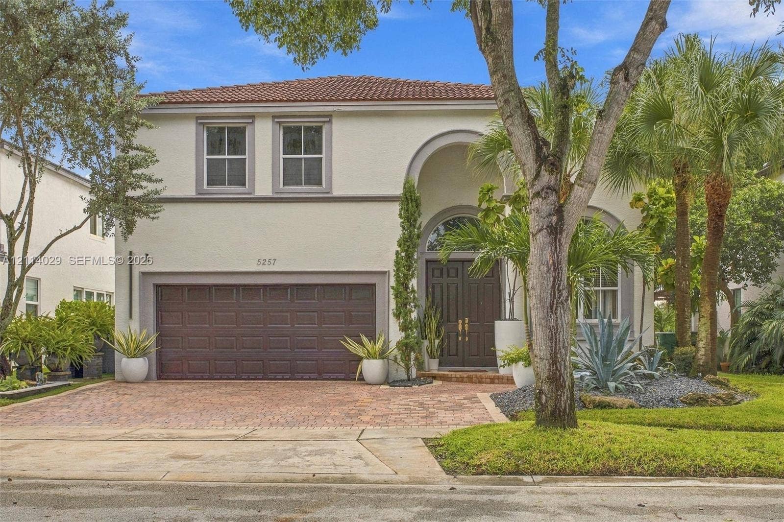 5257 SW 158th Avenue, Miramar, FL 33027 Two-story stucco exterior featuring a barrel tile roof, arched entryway with double doors, and a decorative stone-paved driveway