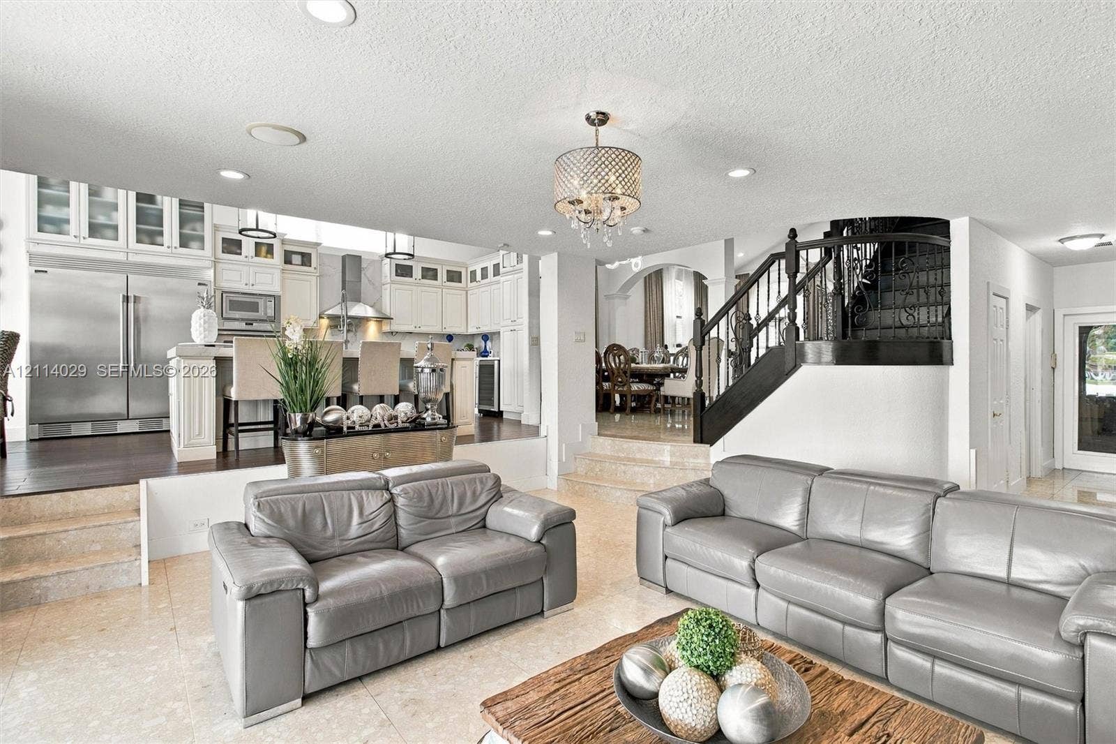 5257 SW 158th Avenue, Miramar, FL 33027 Kitchen featuring white cabinetry, stainless steel appliances, and a central island with bar seating, highlighted by recessed lighting and a decorative chandelier