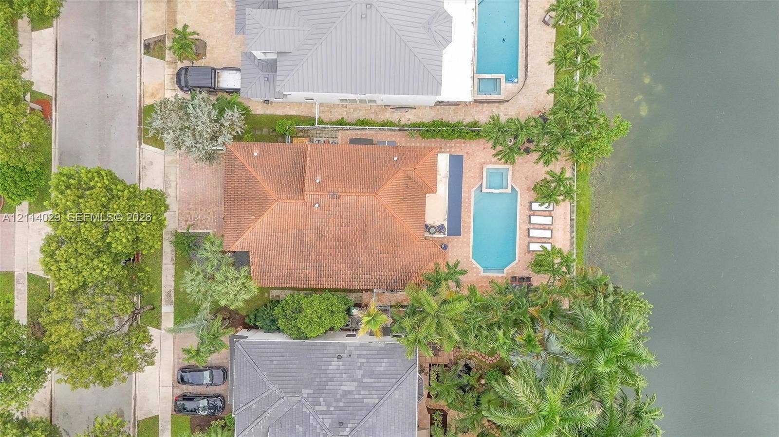 5257 SW 158th Avenue, Miramar, FL 33027 Waterfront property featuring a tile roof, an in-ground pool with an integrated spa, and an expansive paved patio