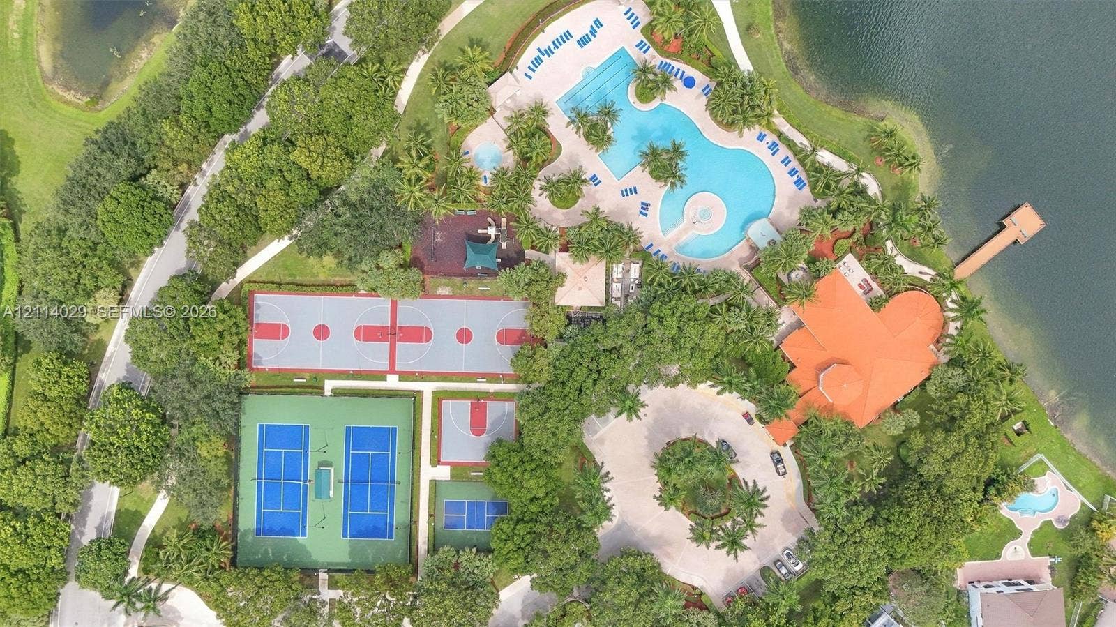 5257 SW 158th Avenue, Miramar, FL 33027 Aerial recreation complex featuring a resort-style swimming pool, two tennis courts, a basketball court, and a wooden lakefront dock