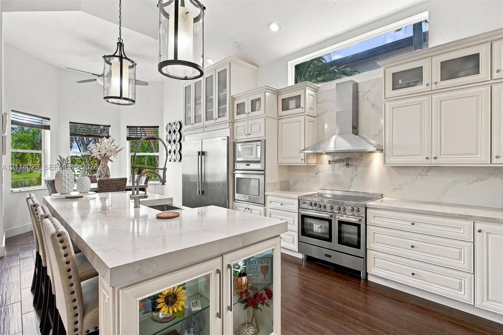 5257 SW 158th Avenue, Miramar, FL 33027 Kitchen featuring white cabinetry with glass-front uppers, solid surface countertops, a professional-grade stainless steel range with matching vent hood, and wood-finish flooring