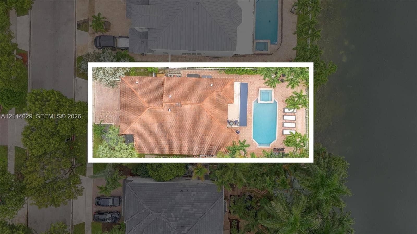 5257 SW 158th Avenue, Miramar, FL 33027 Aerial perspective of a property featuring a tile roof, paved patio, swimming pool, raised spa, and waterfront bulkhead