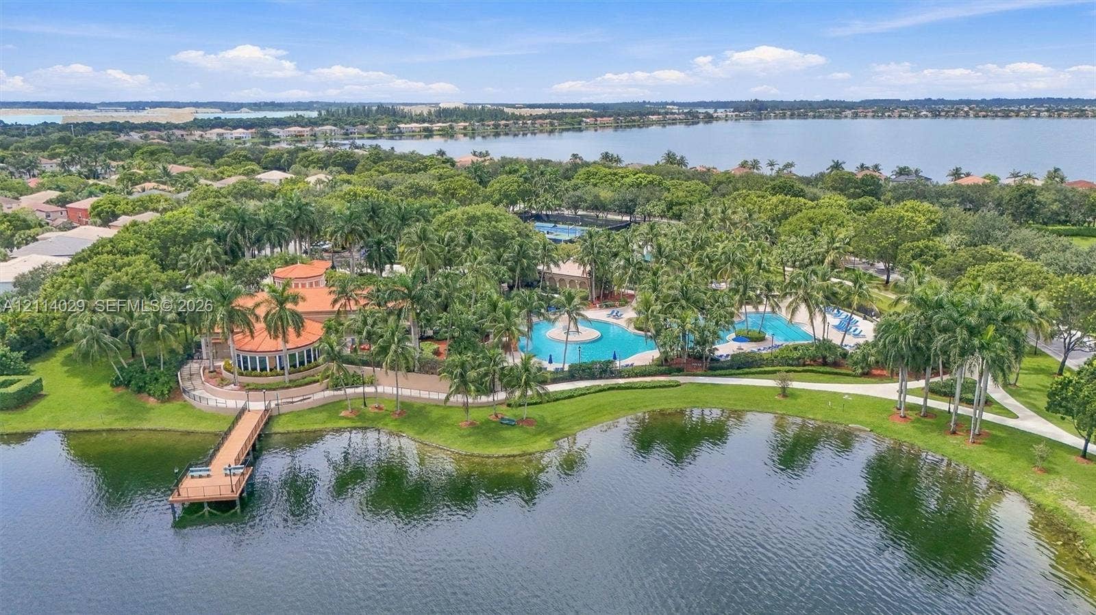 5257 SW 158th Avenue, Miramar, FL 33027 Waterfront community clubhouse featuring a swimming pool, pedestrian dock, manicured landscaping, and palm-lined grounds