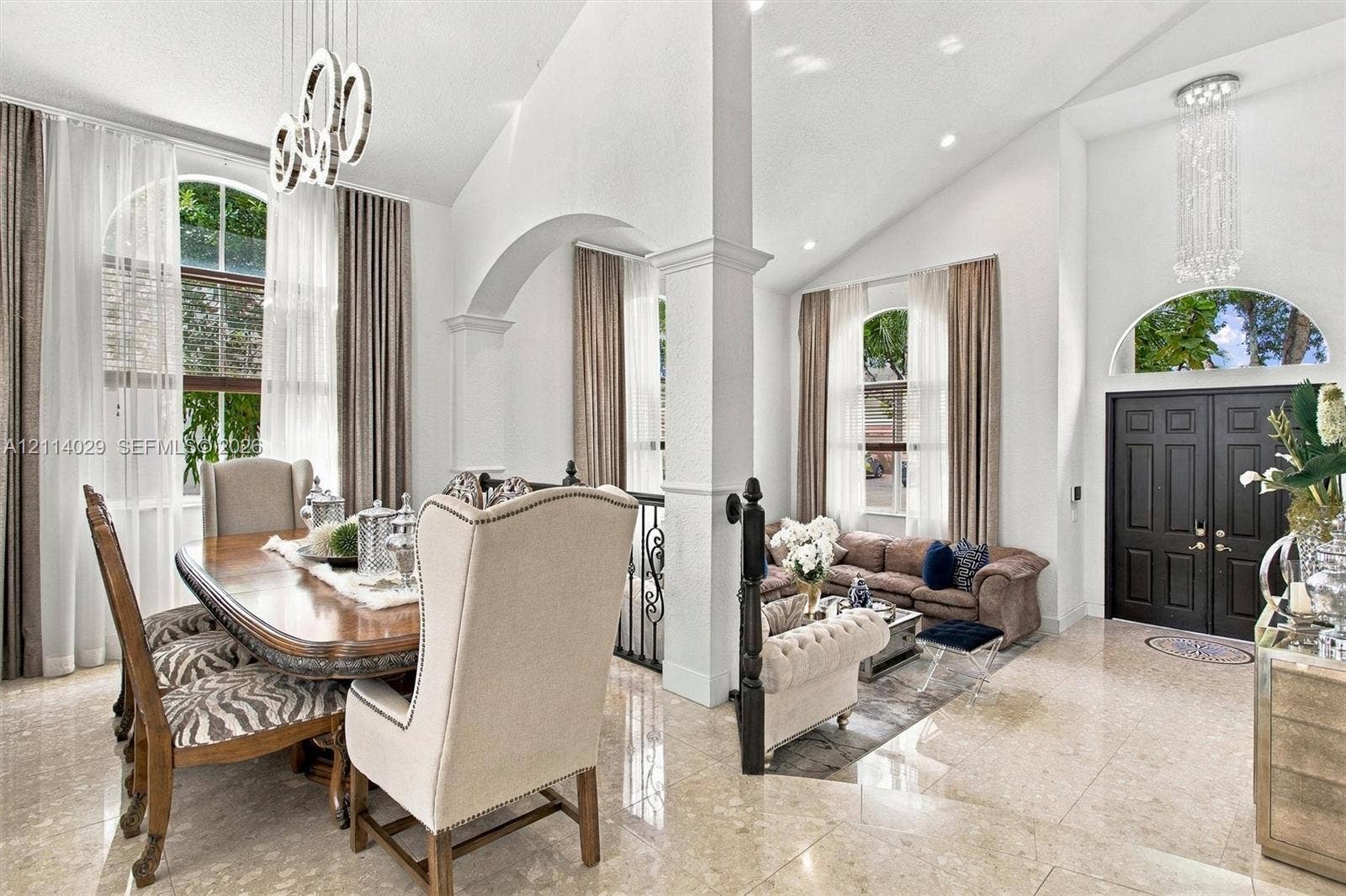 5257 SW 158th Avenue, Miramar, FL 33027 Vaulted ceilings, expansive stone flooring, arched architectural detailing, modern circular pendant lighting, and a double-entry front door with a half-moon transom window