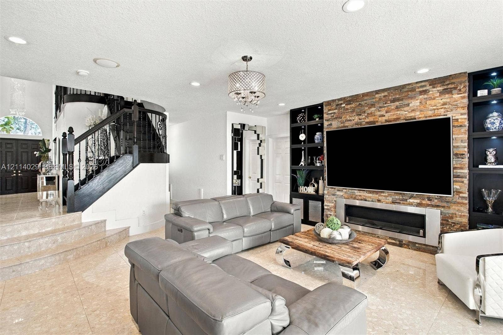 5257 SW 158th Avenue, Miramar, FL 33027 Living area featuring stone-clad accent wall, linear fireplace, built-in black cabinetry, stone flooring, and staircase with black metal railing