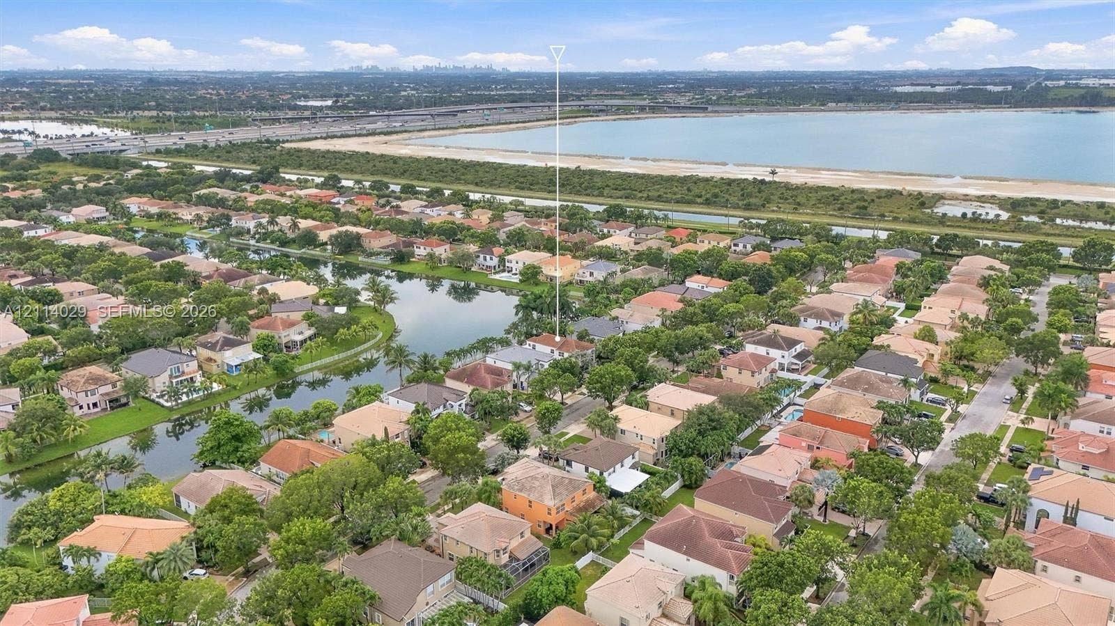 5257 SW 158th Avenue, Miramar, FL 33027 Aerial perspective of a residential property situated in a planned community featuring a lake, tree-lined streets, and proximity to a large body of water