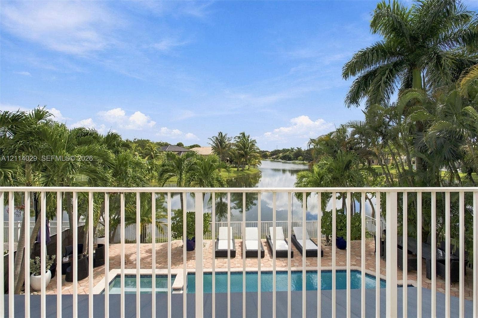 5257 SW 158th Avenue, Miramar, FL 33027 Outdoor patio featuring a swimming pool, integrated spa, stone-paver decking, and metal balcony railing with water frontage