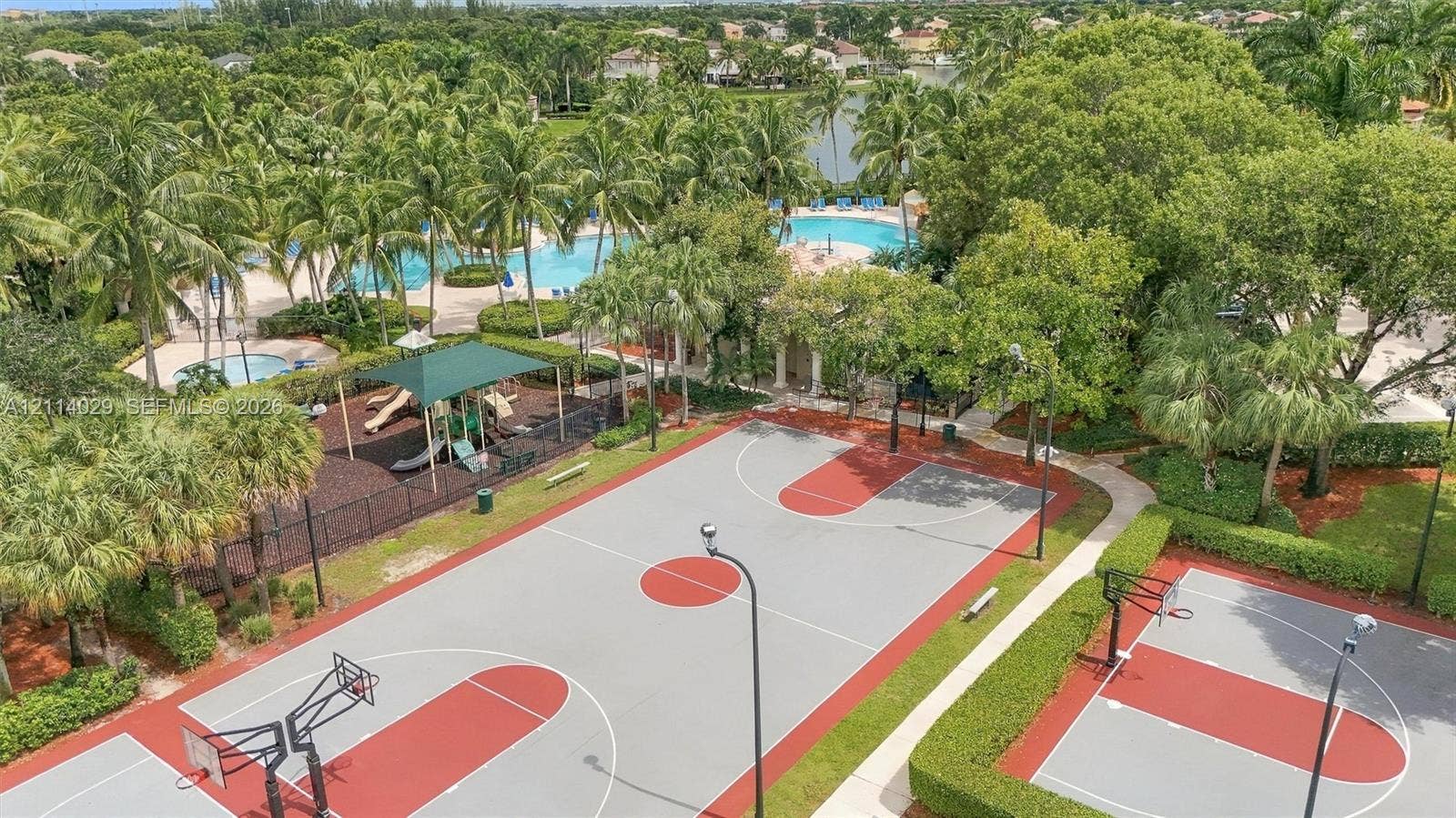 5257 SW 158th Avenue, Miramar, FL 33027 Community recreation area featuring multiple basketball courts, a swimming pool, and a playground area surrounded by mature palm trees and manicured landscaping