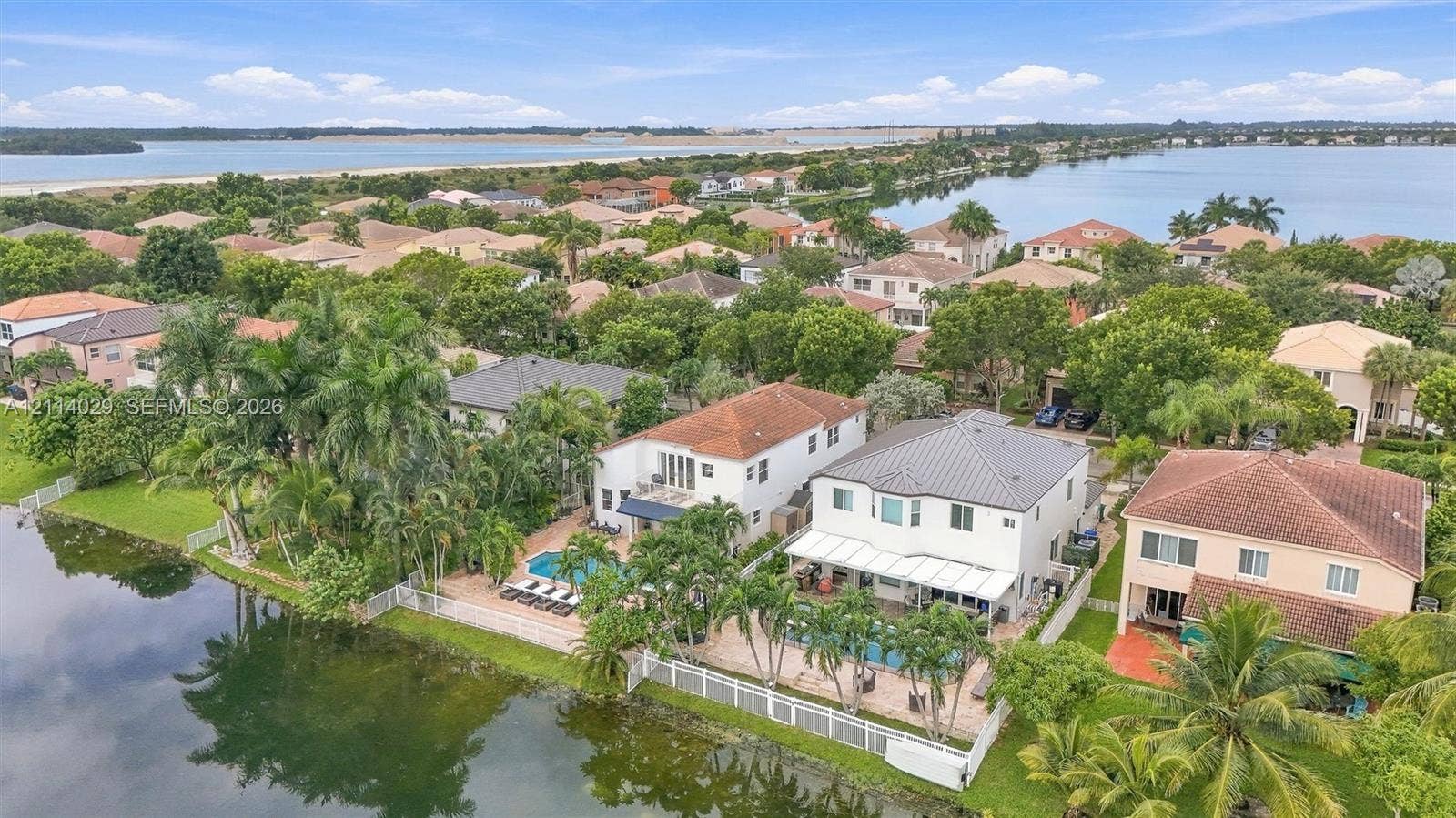 5257 SW 158th Avenue, Miramar, FL 33027 Waterfront property featuring private in-ground swimming pools, paved pool decks, and white perimeter fencing