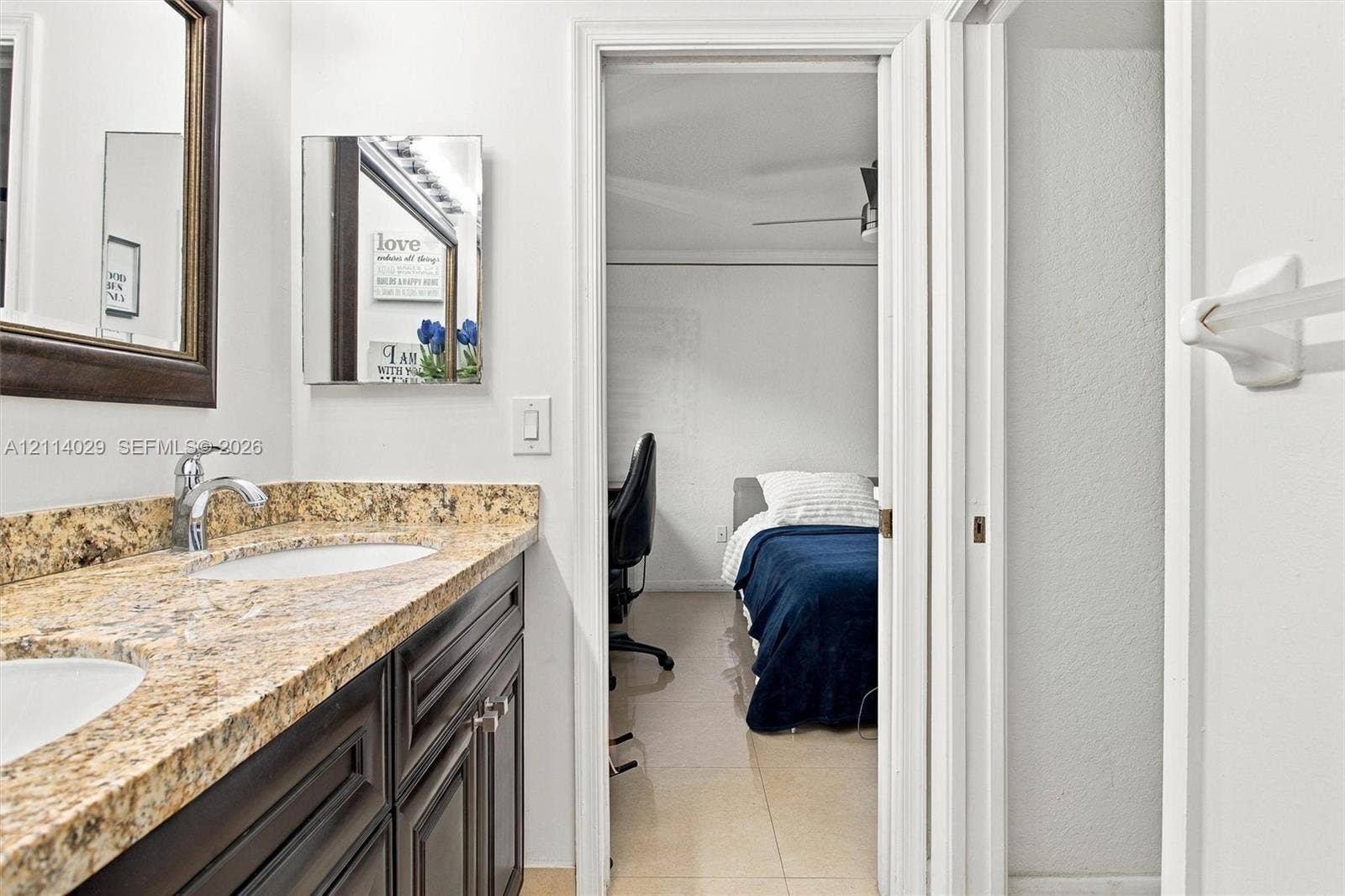 5257 SW 158th Avenue, Miramar, FL 33027 Double-sink vanity featuring dark-toned cabinetry, stone-finish countertops, wall-mounted mirror, and metal fixtures