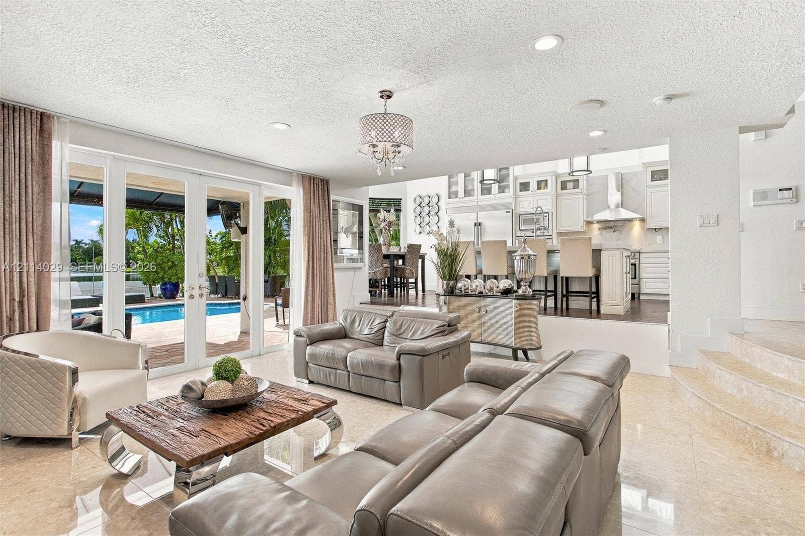 5257 SW 158th Avenue, Miramar, FL 33027 Open-concept floor plan featuring polished stone flooring, recessed lighting, white cabinetry, and multi-panel glass doors with exterior patio and pool access