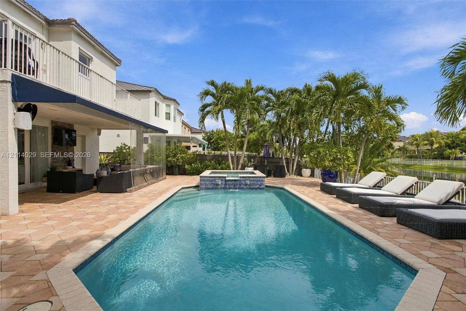 5257 SW 158th Avenue, Miramar, FL 33027 In-ground pool featuring a spillover spa with decorative tile inlay, set within a paved patio area under a covered lanai