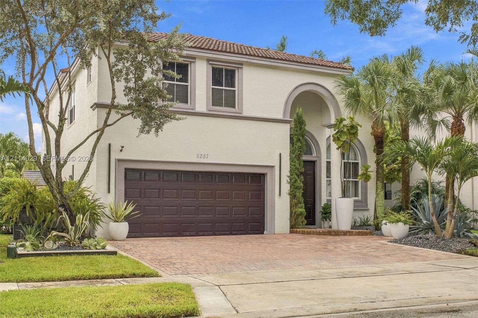 5257 SW 158th Avenue, Miramar, FL 33027 Stucco exterior featuring an arched entryway, terracotta-style roof tiles, a paver driveway, and a two-car garage
