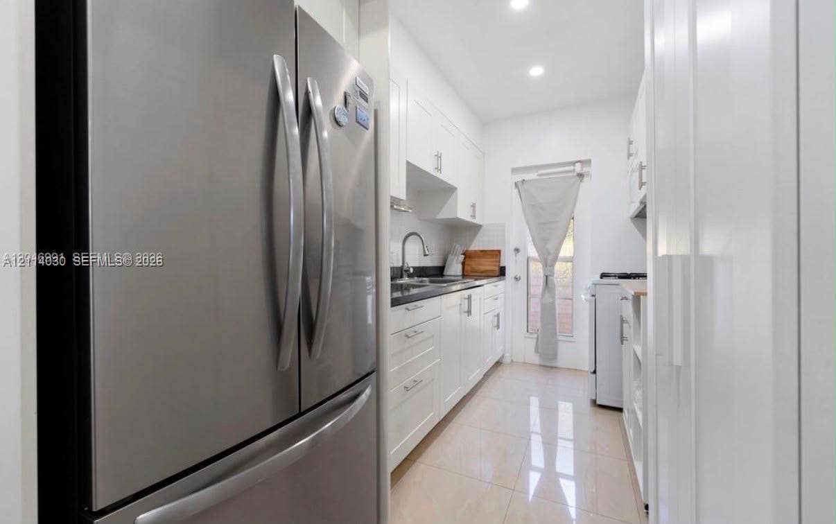 8550 Byron Avenue, #2H, Miami Beach, FL 33141 Kitchen featuring white shaker-style cabinetry, dark stone countertops, stainless steel refrigerator, recessed lighting, and tile flooring