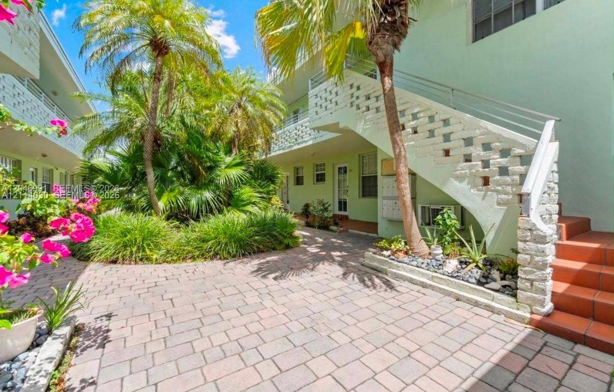 8550 Byron Avenue, #2H, Miami Beach, FL 33141 Exterior courtyard featuring stone paver flooring, open-air staircases with decorative masonry accents, and mature palm landscaping