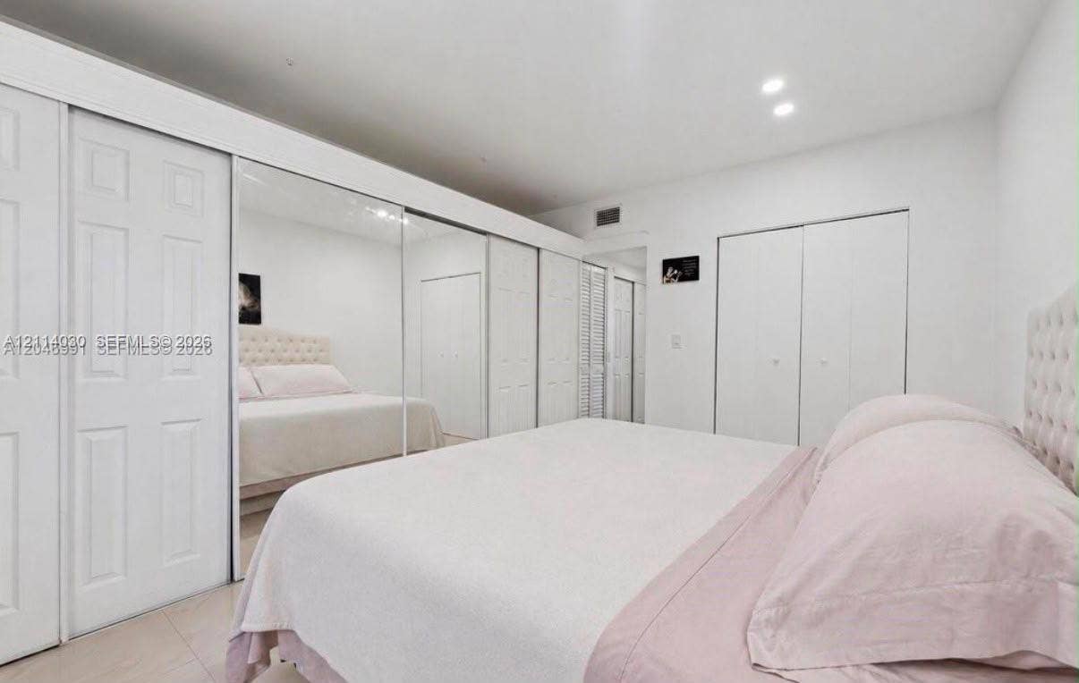 8550 Byron Avenue, #2H, Miami Beach, FL 33141 Full-wall mirrored sliding closet doors, expansive white cabinetry, and recessed lighting