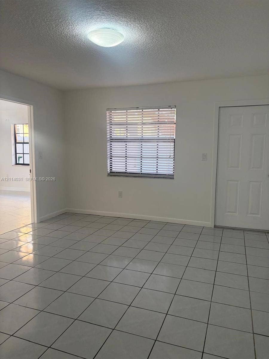 Ceramic tile flooring, neutral wall finishes, flush-mount ceiling lighting, and a six-panel interior door