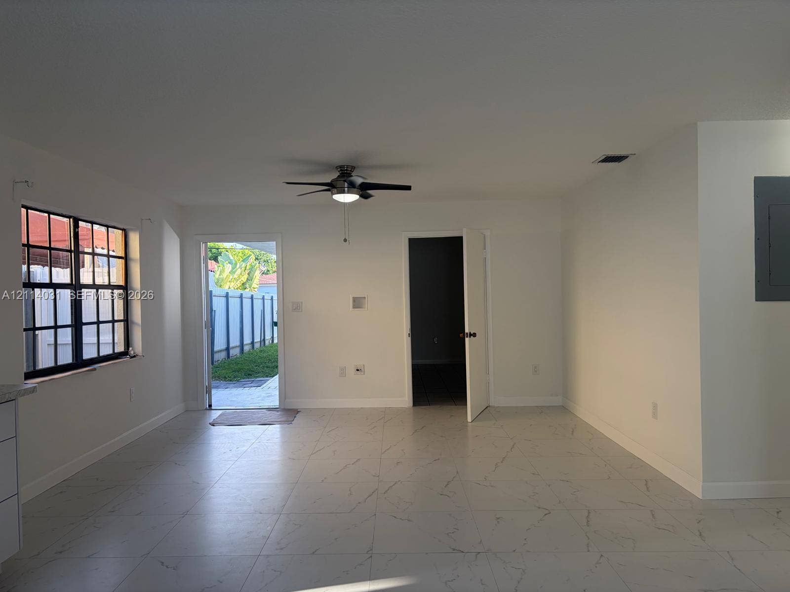 Large-format tile flooring, multi-pane window, ceiling fan with integrated lighting, and exterior access door