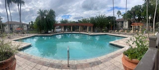 4177 N Haverhill Road, #821, West Palm Beach, West Palm Beach, FL 33417 Swimming pool with a paved deck, built-in wooden pergola, and mature landscaping