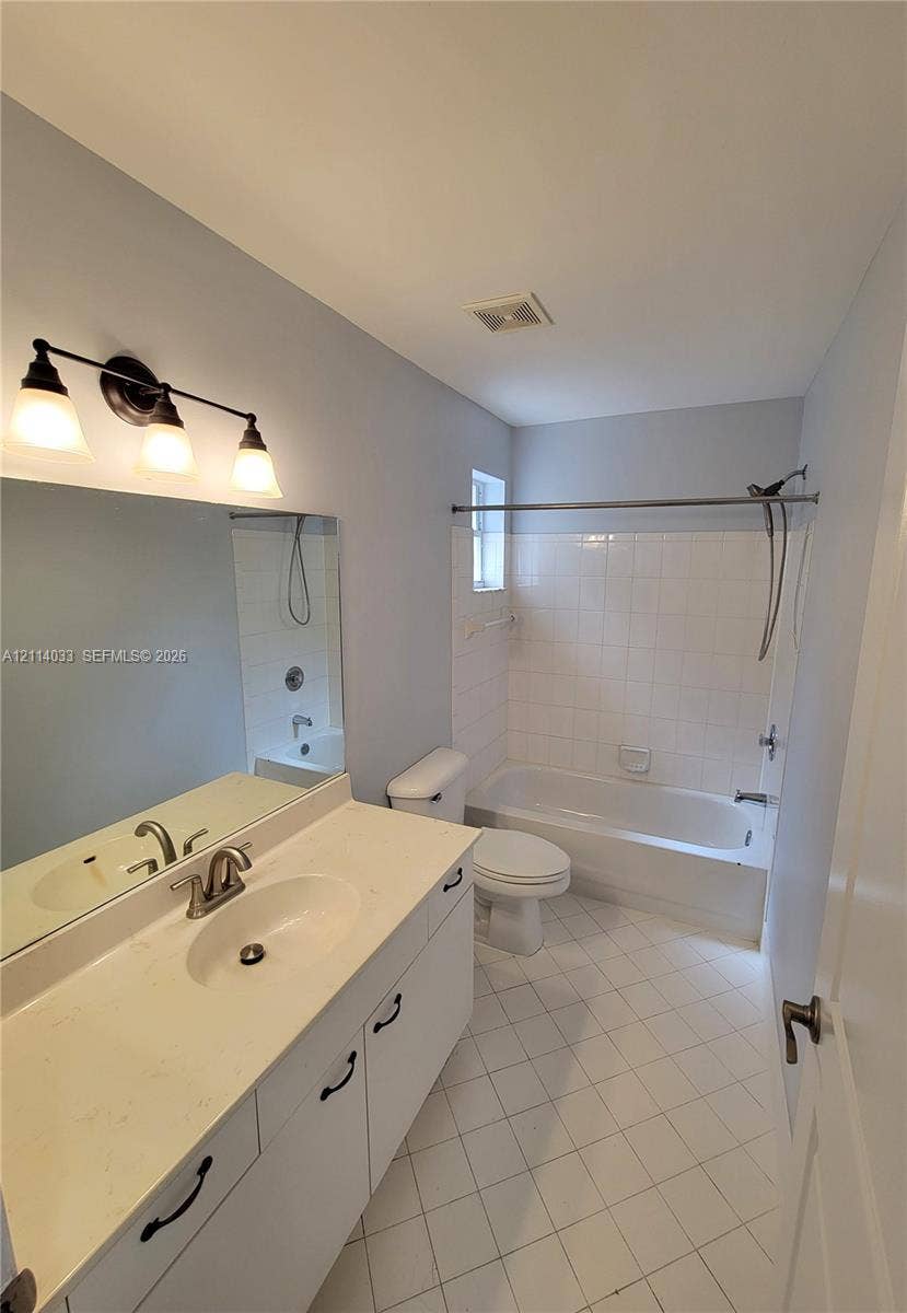 683 NW 88th Drive, Coral Springs, Coral Springs, FL 33071 Bathroom featuring a white vanity with a solid surface countertop, an oval undermount sink, a three-light fixture, and a tub-shower combination with ceramic tile surround